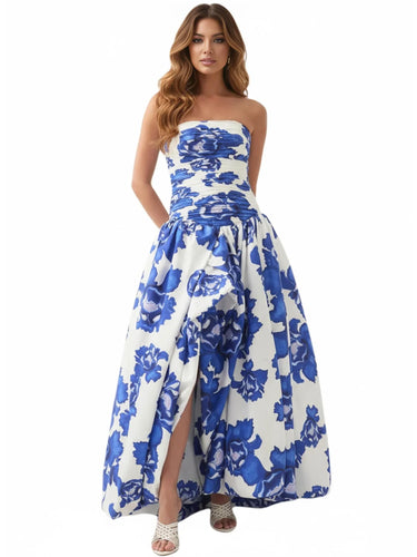 Woman wearing a blue floral strapless long bubble dress with a high slit on a white background